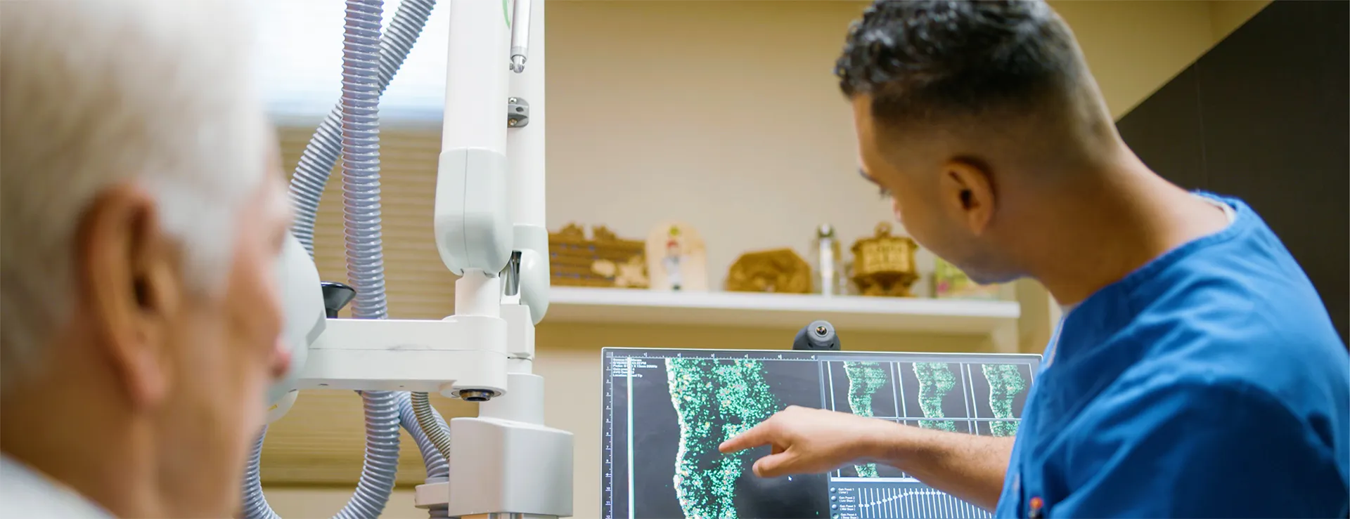 A radiologist looking and pointing at a computer screen and showing an image to a patient.